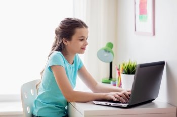 people, children and technology concept - girl typing on laptop computer at home