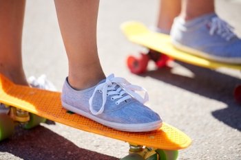 summer, extreme sport and people concept - close up of feet in shoes riding short modern cruiser skateboards on city street