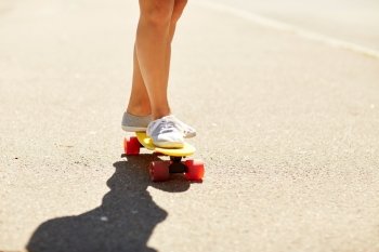 summer, extreme sport and people concept - legs of teenage girl or young woman riding skateboard on road