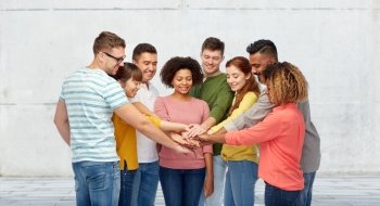 diversity, teamwork, cooperation, ethnicity and people concept - international group of happy smiling men and women holding hands together over wall background. international group of happy people holding hands