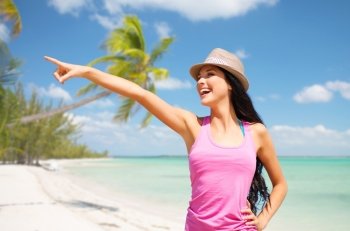 summer holidays, travel, people and vacation concept - happy young woman in hat pointing finger over exotic tropical beach with palm trees and sea shore background. happy young woman in hat on summer beach