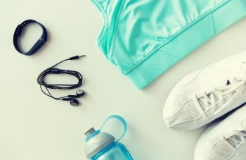sport, fitness, healthy lifestyle and objects concept - close up of female sports clothing, heart-rate watch, earphones and bottle set. sportswear, bracelet, earphones and bottle set