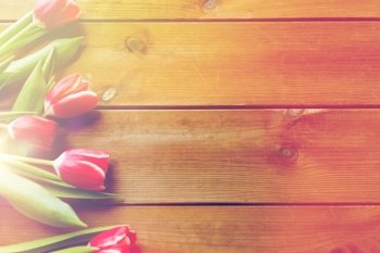 flora, gardening and plant concept - close up of red tulip flowers on wooden table with copy space. close up of tulip flowers on wooden table