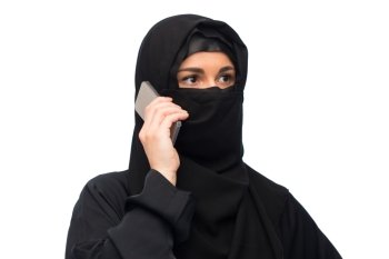 technology, communication and people concept - muslim woman in hijab calling on smartphone over white background. muslim woman in hijab over white background