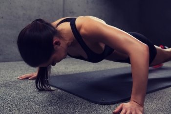 fitness, sport, people and exercising concept - woman doing push-ups in gym. woman doing push-ups in gym