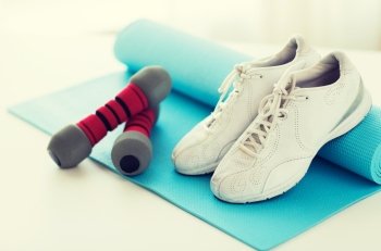 sport, fitness, healthy lifestyle and objects concept - close up of sneakers, dumbbells and sports mat. close up of sneakers, dumbbells and sports mat