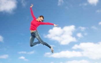 happiness, freedom, motion and people concept - happy young woman jumping or dancing in air over blue sky and clouds background. happy young woman jumping in air or dancing