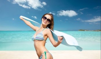 people, summer holidays and vacation concept - beautiful woman in bikini and sunglasses with towel over exotic tropical beach background. woman in bikini and sunglasses with towel on beach