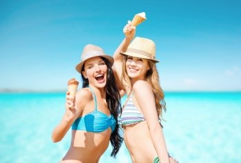 summer holidays, vacation, food, travel and people concept - smiling young women eating ice cream on beach over sea and blue sky background. smiling women eating ice cream on beach