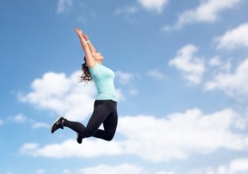 sport, fitness, motion and people concept - happy smiling young woman jumping in air or dancing over blue sky background. happy sporty young woman jumping in blue sky