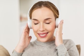 leisure, technology and people concept - smiling woman with headphones listening to music at home. woman with headphones listening to music at home