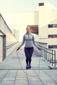 fitness, sport, people, exercising and lifestyle concept - happy woman skipping with jump rope outdoors. happy woman exercising with jump-rope outdoors