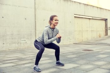 fitness, sport, exercising and healthy lifestyle concept - happy woman doing squats outdoors. happy woman doing squats and exercising outdoors