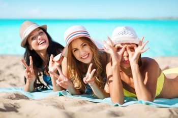 summer holidays, vacation, travel and people concept - group of smiling young women in hats lying over exotic tropical beach with background. group of happy women in hats sunbathing on beach