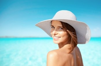 summer holidays, vacation, travel and people concept - smiling young woman in sun hat on beach over sea and blue sky background. smiling young woman in sun hat on summer beach