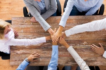 business, teamwork, gesture and corporate concept - group of people sitting at office table and holding hands. business people holding hands at office table