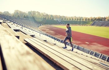 fitness, sport, exercising and people concept - happy young man running upstairs on stadium. happy young man running upstairs on stadium