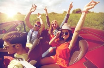 leisure, road trip, travel and people concept - happy friends driving in cabriolet car at country and waving hands. happy friends driving in cabriolet car at country
