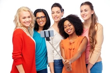 diversity, race, ethnicity, technology and people concept - international group of happy smiling different women over white taking picture with smartphone on selfie stick. international group of happy women taking selfie