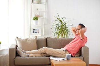 comfort and people concept - man in glasses relaxing on sofa at home. man in glasses relaxing on sofa at home