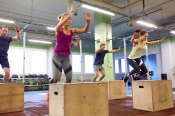 fitness, sport, training and exercising concept - group of people doing box jumps in gym (motion blurred image). group of people doing box jumps exercise in gym