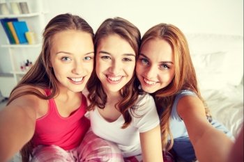 friendship, people, pajama party and fun concept - happy friends or teenage girls taking selfie at home. happy friends or teen girls taking selfie at home