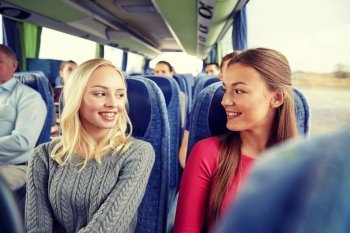transport, tourism, friendship, road trip and people concept - happy young women sitting and talking in travel bus. happy young women talking in travel bus