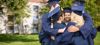 education, graduation and people concept - group of happy international students in mortar boards and bachelor gowns hugging over campus building background. happy students or bachelors hugging