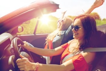 summer holidays, road trip, vacation, travel and people concept - smiling young women driving in in cabriolet car. smiling young women driving in cabriolet car