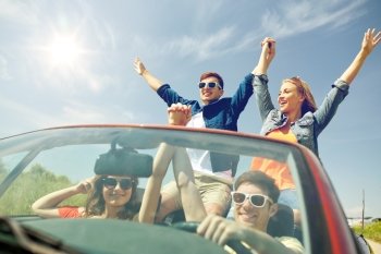 leisure, road trip, travel and people concept - happy friends driving in cabriolet car at country and waving hands. happy friends driving in cabriolet car at country