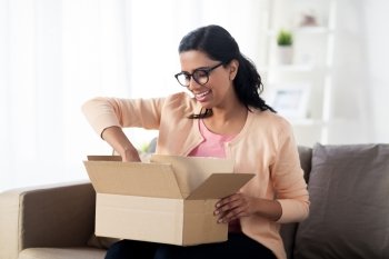 people, delivery, shipping and postal service concept - happy young indian woman holding open cardboard box or parcel at home. happy young indian woman with parcel box at home