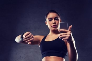 sport, fitness, technology and people concept - young woman with heart-rate watch and smartphone in gym. woman with heart-rate watch and smartphone in gym