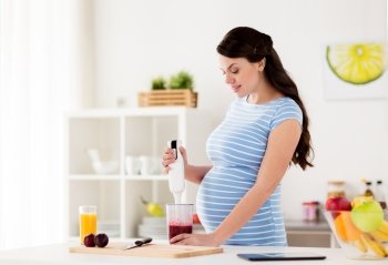 healthy eating, cooking, pregnancy and people concept - pregnant woman with blender preparing fruit smoothie drink at home kitchen. pregnant woman with blender cooking fruits at home