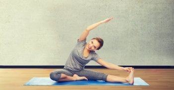 fitness, sport, people and healthy lifestyle concept - happy woman making yoga and stretching on mat over room or gym background. happy woman making yoga and stretching on mat