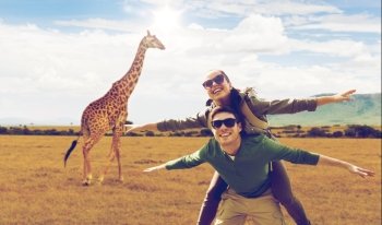 travel, tourism and people concept - happy couple with backpacks having fun over giraffe in african savannah background. happy couple with backpacks having fun in africa