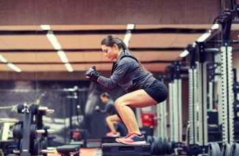 fitness, sport, exercising and people concept - woman doing squats on platform in gym. woman doing squats on platform in gym