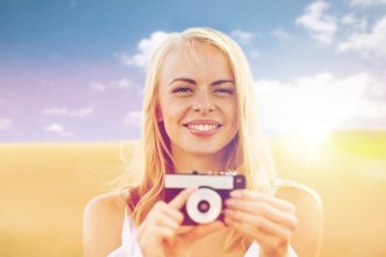 nature, summer holidays, vacation and people concept - happy smiling young woman with film camera outdoors. happy young woman with film camera outdoors