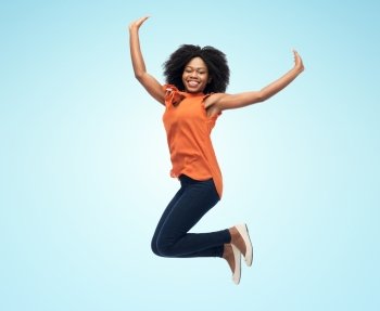 people, ethnicity and motion concept - happy african american young woman jumping over blue background. happy african american woman jumping over white