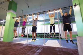 sport, fitness, exercising and training concept - group of people hanging at horizontal bar in gym. group of people hanging at horizontal bar in gym