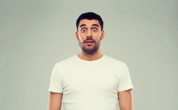 emotion, advertisement and people concept - scared man in white t-shirt over gray background. scared man in white t-shirt over gray background