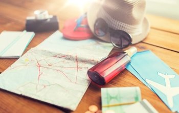 summer vacation, tourism and objects concept - close up of travel map, airplane tickets, money and personal accessories. close up of travel map, tickets, money and stuff