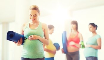 pregnancy, sport, fitness, people and healthy lifestyle concept - happy pregnant woman with mat in gym. happy pregnant woman with mat in gym