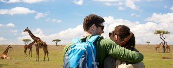 travel, tourism and people concept - happy couple with backpacks hugging over african savannah and giraffes background. happy couple with backpacks traveling