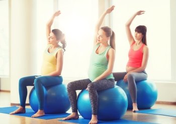 pregnancy, sport, fitness, people and healthy lifestyle concept - group of happy pregnant women exercising on ball in gym. happy pregnant women exercising on fitball in gym. happy pregnant women exercising on fitball in gym