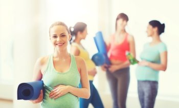 pregnancy, sport, fitness, people and healthy lifestyle concept - happy pregnant woman with mat in gym. happy pregnant woman with mat in gym. happy pregnant woman with mat in gym