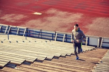 fitness, sport, exercising and people concept - happy young man running upstairs on stadium. happy young man running upstairs on stadium. happy young man running upstairs on stadium