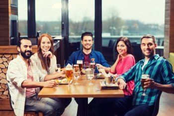 leisure, eating, food and drinks, people and holidays concept - smiling friends having dinner and drinking beer at restaurant or pub. friends dining and drinking beer at restaurant. friends dining and drinking beer at restaurant