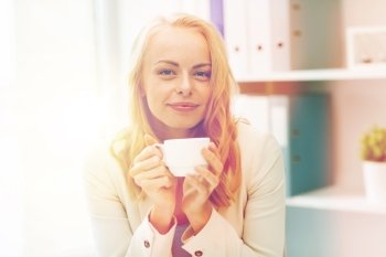 business, education and people concept - happy young businesswoman or student girl drinking coffee at office. happy businesswoman drinking coffee at office. happy businesswoman drinking coffee at office
