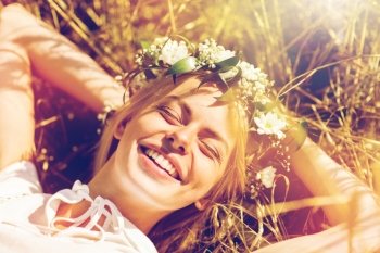 nature, summer holidays, vacation and people concept - happy smiling woman in wreath of flowers lying on straw. happy woman in wreath of flowers lying on straw. happy woman in wreath of flowers lying on straw