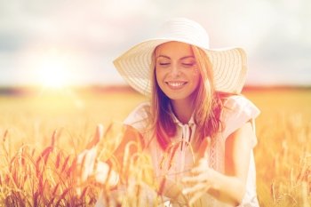 nature, summer holidays, vacation and people concept - happy young woman in white dress and sun hat enjoying sun on cereal field. happy young woman in sun hat on cereal field. happy young woman in sun hat on cereal field